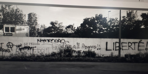 Die Baustelle beim Bässlergut mit einer Bretterwand voller Parolen: NoBorders, Liberté!, Free all Prisoners!!